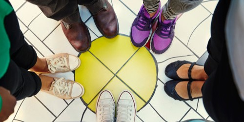 5 pair of feet with shoes in various colors in a circle