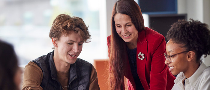 Lärare står över axeln på två studenter