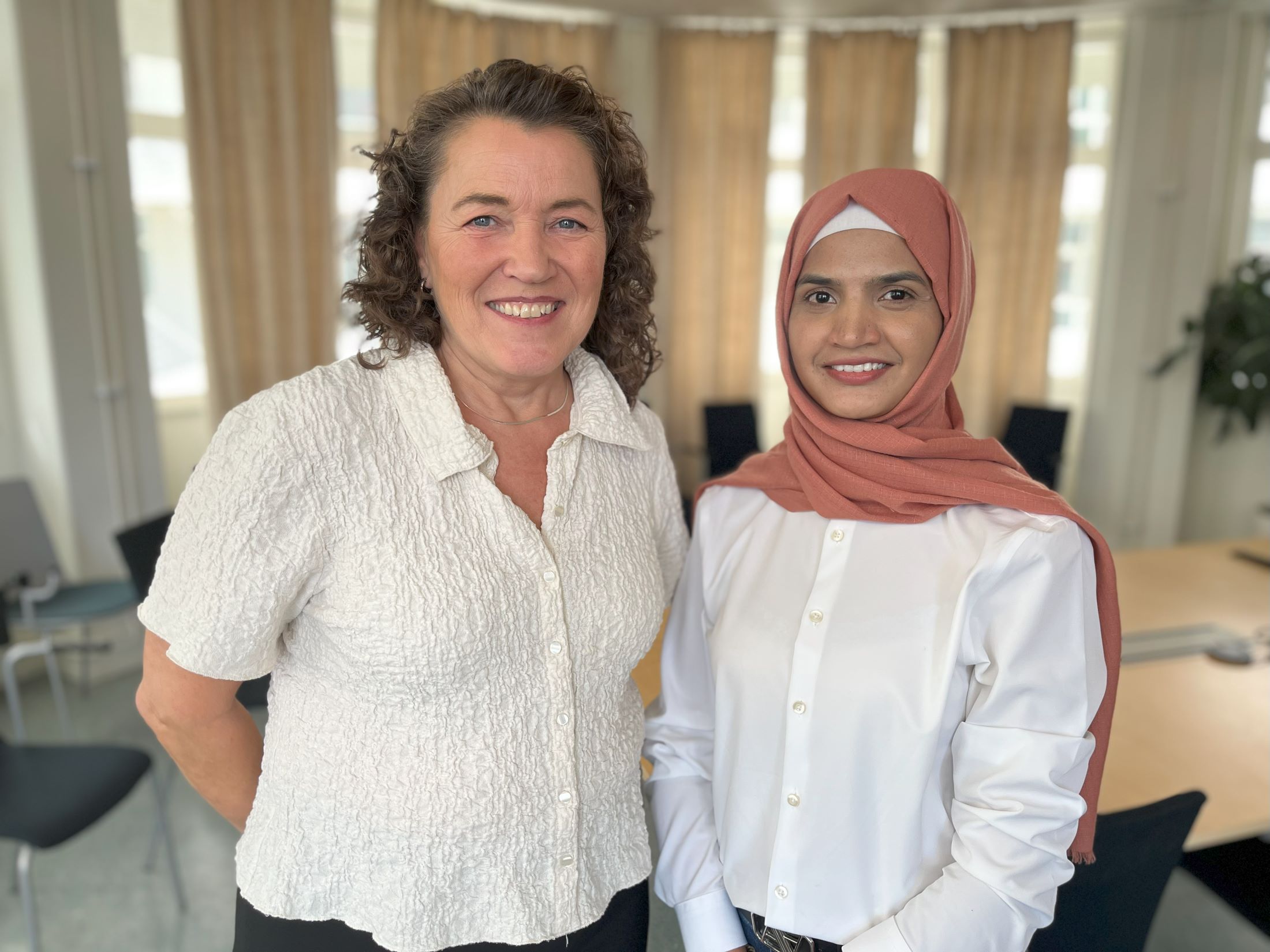 Två kvinnor står bredvid varandra i en skolsal.