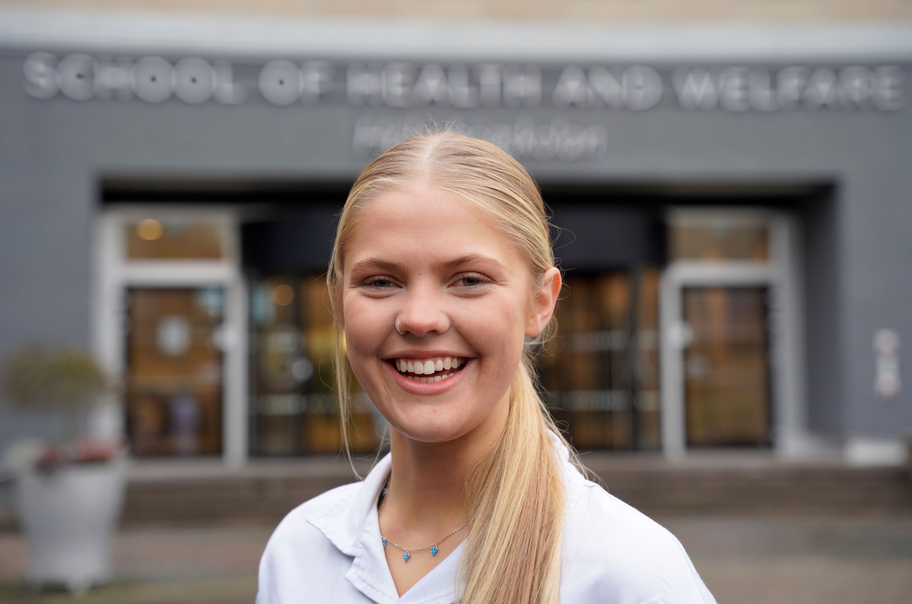 Ung tjej framför byggnad.